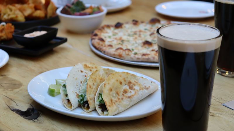 A plate of three tacos and a beer.